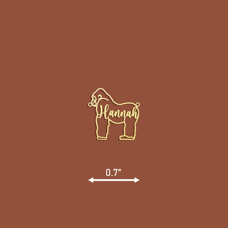 May include: Gold-colored wooden cutout of a gorilla with the name "Hannah" written inside. The cutout is 0.7 inches tall.
