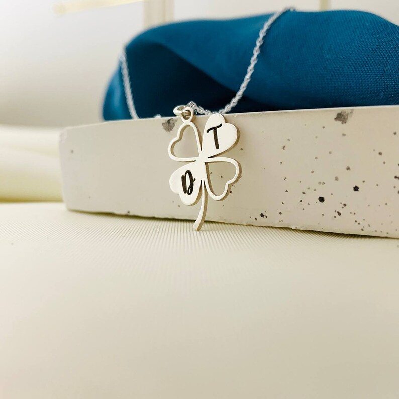 Peut inclure: Un collier en argent avec un pendentif en forme de tr&egrave;fle &agrave; quatre feuilles. Le pendentif porte les lettres "D" et "T" grav&eacute;es.