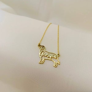 May include: Gold necklace with a dog silhouette pendant. The dog's name, "Georgia", is cut out of the pendant.