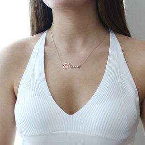 May include: A rose gold necklace with a paw print charm and the name "Ocean" written in cursive.