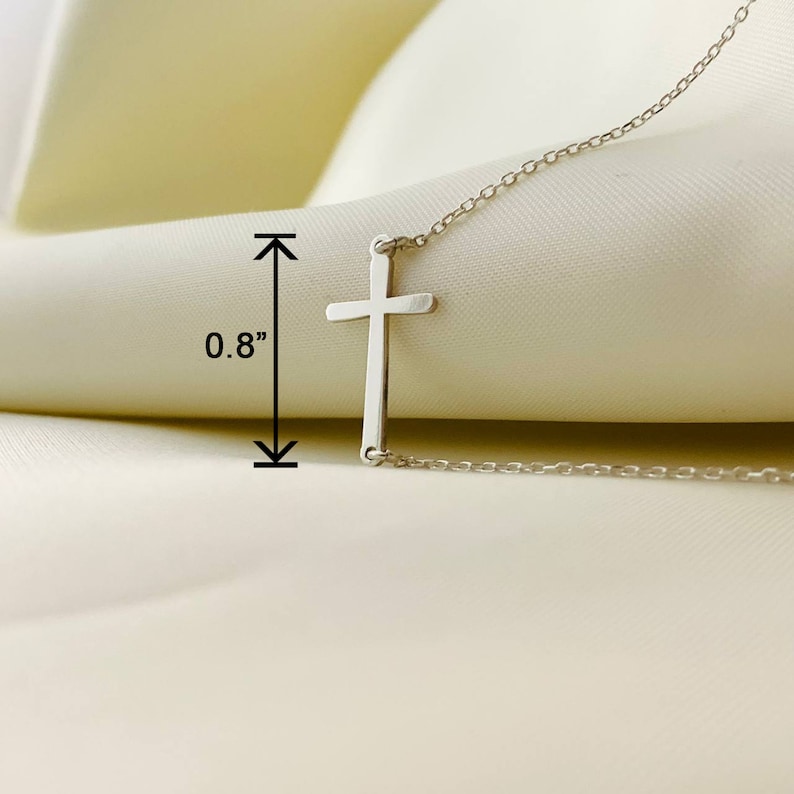 May include: A silver cross pendant necklace with a chain. The cross is 0.8 inches tall.