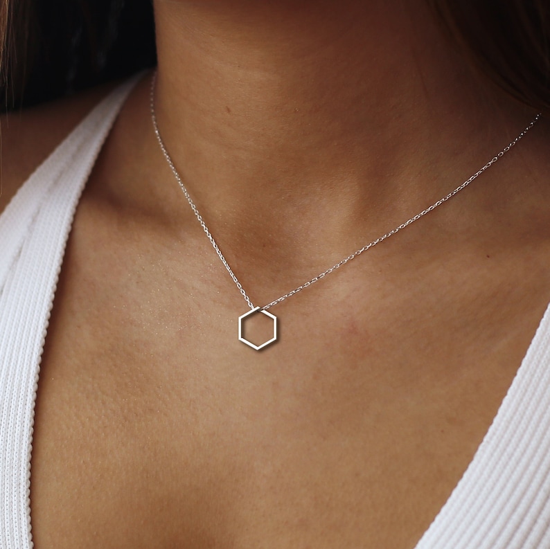 May include: A silver chain necklace with a hexagon pendant.