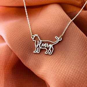 May include: A silver necklace with a cat-shaped pendant. The cat's outline is formed by the name "Henry" in cursive.