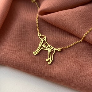 K&ouml;nnte beinhalten: Goldkette mit einem Anh&auml;nger in Form einer Hundesilhouette. Die Silhouette des Hundes ist mit dem Wort "Lola" gef&uuml;llt.