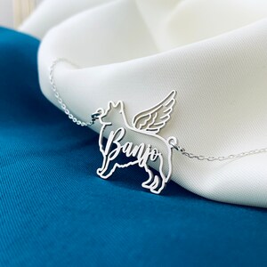 May include: Silver necklace with a cutout of a dog with wings and the name "Banjo" written on it.
