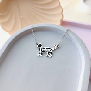 May include: Silver necklace with a black cat silhouette pendant. The cat's name, "Onyx", is written inside the silhouette.