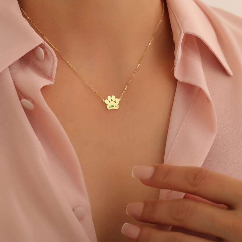 May include: Gold paw print necklace with the name "Willow" engraved on it.