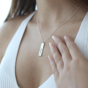 Puede incluir: Un collar de plata con un colgante rectangular que dice "Irrompible".