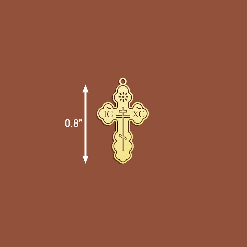 May include: A gold-coloured metal cross pendant with intricate details. The cross features the inscription "IC XC" and a small circle at the top. The pendant measures 0.8 inches in height.