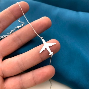 Op de afbeelding: Een zilveren ketting met een delicate vliegtuighanger. De hanger is een eenvoudige silhouet van een vliegtuig.