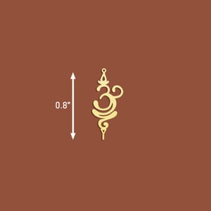 K&ouml;nnte beinhalten: Goldfarbener Metallanh&auml;nger mit einem filigranen Design des Om-Symbols, etwa 2 cm hoch.