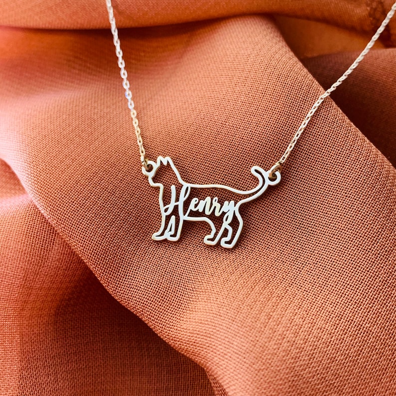 May include: A silver necklace with a cat-shaped pendant. The cat's outline is formed by the name "Henry" in cursive.