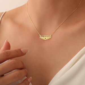 Puede incluir: Collar de oro con un colgante de placa con el nombre "ALYSSA" con alas y una estrella en el centro.