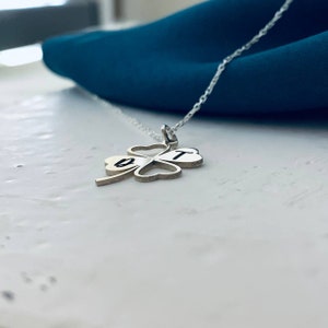 Peut inclure: Un collier en argent avec un pendentif en forme de tr&egrave;fle &agrave; quatre feuilles. Le pendentif porte les lettres "B" et "T" grav&eacute;es.