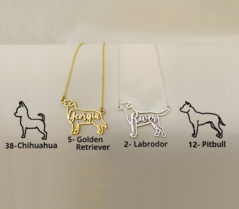 K&ouml;nnte beinhalten: Drei goldene und silberne Halsketten mit Hundesilhouetten. Die Halsketten tragen die Namen "Georgia", "River" und eine leere Stelle. Die Hundesilhouetten sind ein Chihuahua, ein Golden Retriever, ein Labrador Retriever und ein Pitbull.