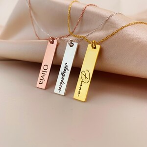 Puede incluir: Tres collares de barra de oro con nombres personalizados grabados en ellos. Los nombres son Olivia, Angelina y Diana.