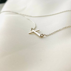 Op de afbeelding: Een zilveren ketting met een eenvoudige zilveren kruis hanger.