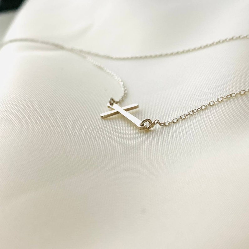 Op de afbeelding: Een zilveren ketting met een eenvoudige zilveren kruis hanger.