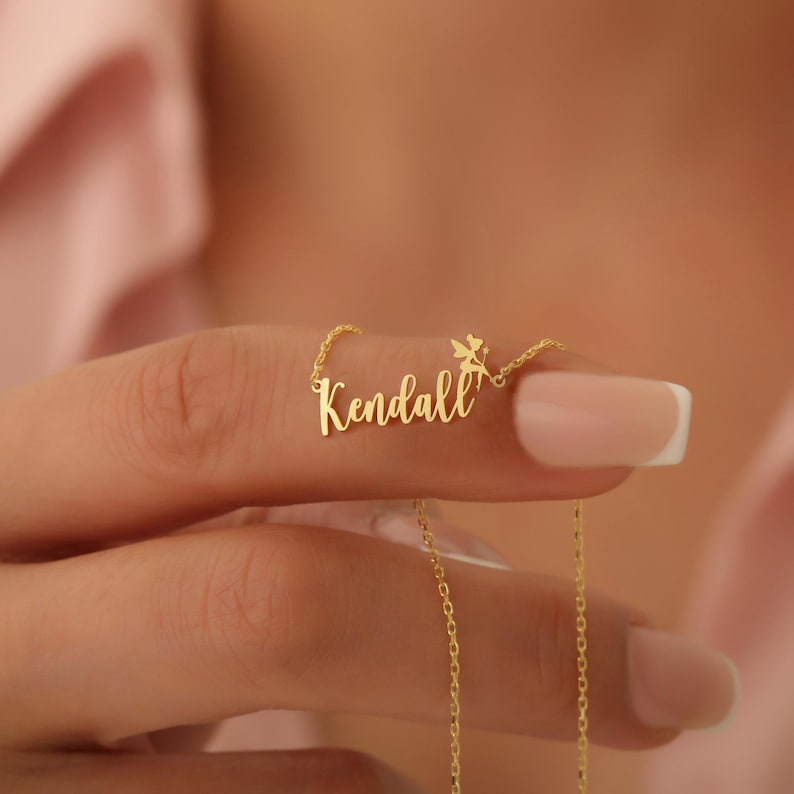Pu&ograve; includere: Collana in oro con il nome "Kendall" e un piccolo ciondolo a forma di fata.