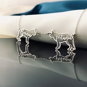 May include: A silver necklace with two dog silhouettes, one with the name "Bernie" and the other with the name "Petunia".