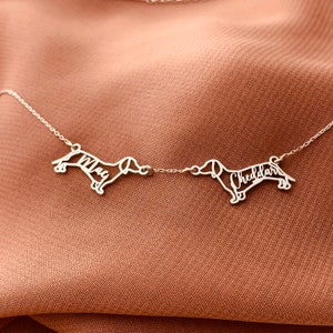 May include: Silver dachshund silhouette necklace with the names "Max" and "Cheddar" inscribed on each dachshund.