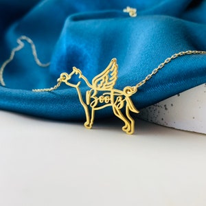 May include: Gold necklace with a dog silhouette pendant. The dog has wings and the name "Boots" is written inside the silhouette.