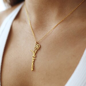 May include: A gold necklace with a delicate daffodil pendant and the name "Veronica" inscribed on the stem.