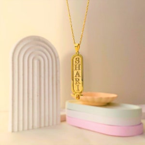 K&ouml;nnte beinhalten: Goldkette mit einem Anh&auml;nger, auf dem das Wort "SHARI" in einem alten &auml;gyptischen Hieroglyphenstil eingraviert ist.