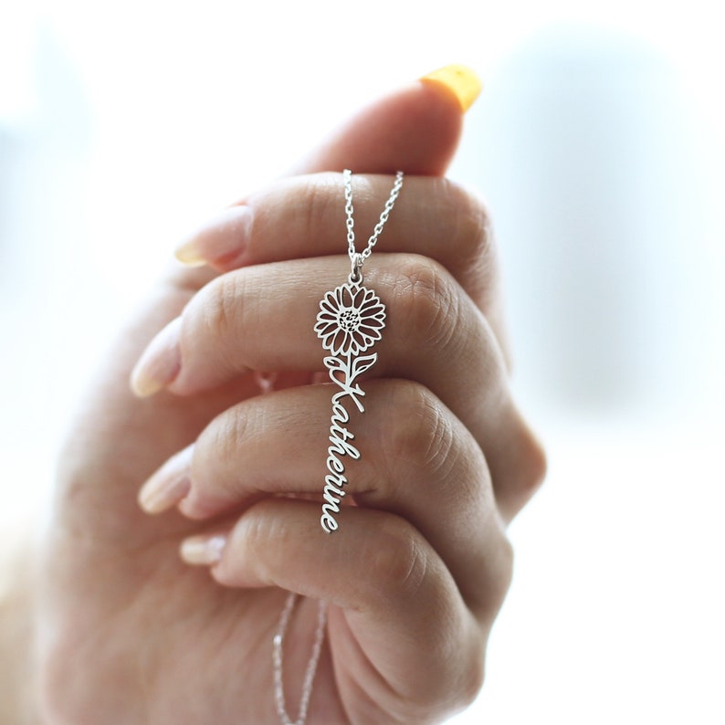 May include: Silver necklace with a sunflower pendant and the name "Katherine" written in cursive.