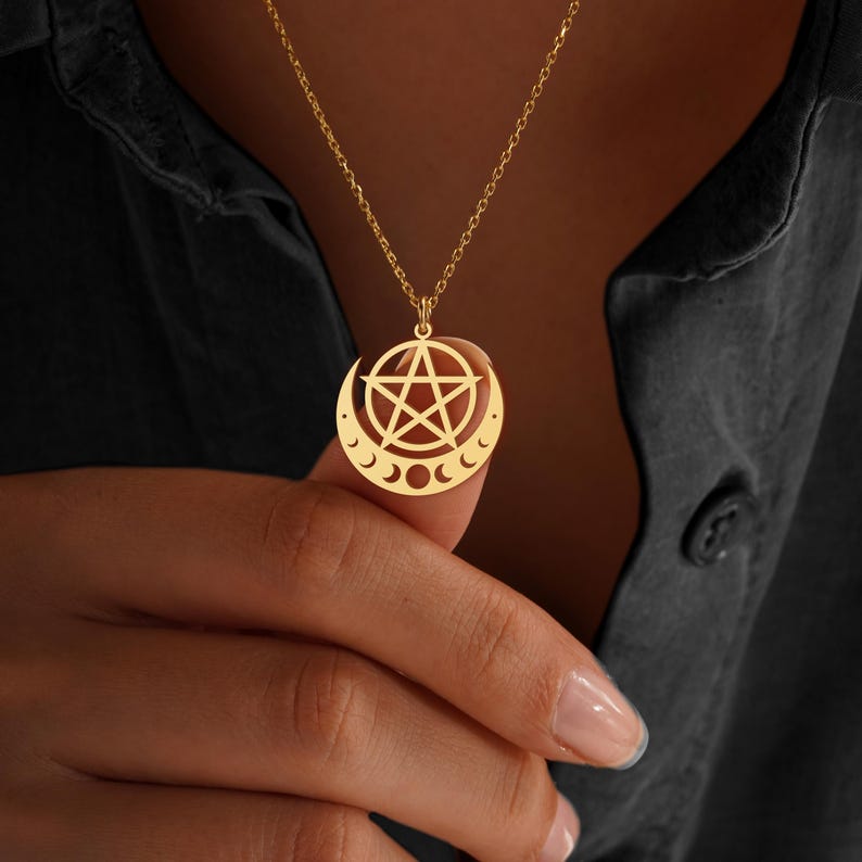 Peut inclure: Collier pendentif dor&eacute; avec un pentagramme dans un croissant de lune. La cha&icirc;ne du collier est fine et se d&eacute;tache sur un fond sombre. Le pendentif comporte &eacute;galement trois petites phases de lune.