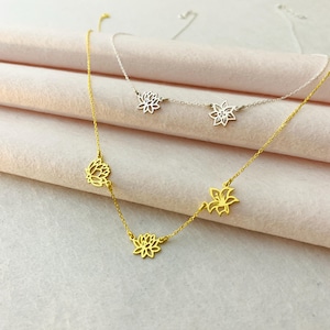 K&ouml;nnte beinhalten: Zwei zarte Halsketten mit mehreren Blumenanh&auml;ngern. Eine Halskette ist golden mit drei Blumenanh&auml;ngern, die andere ist silber mit zwei Blumenanh&auml;ngern.