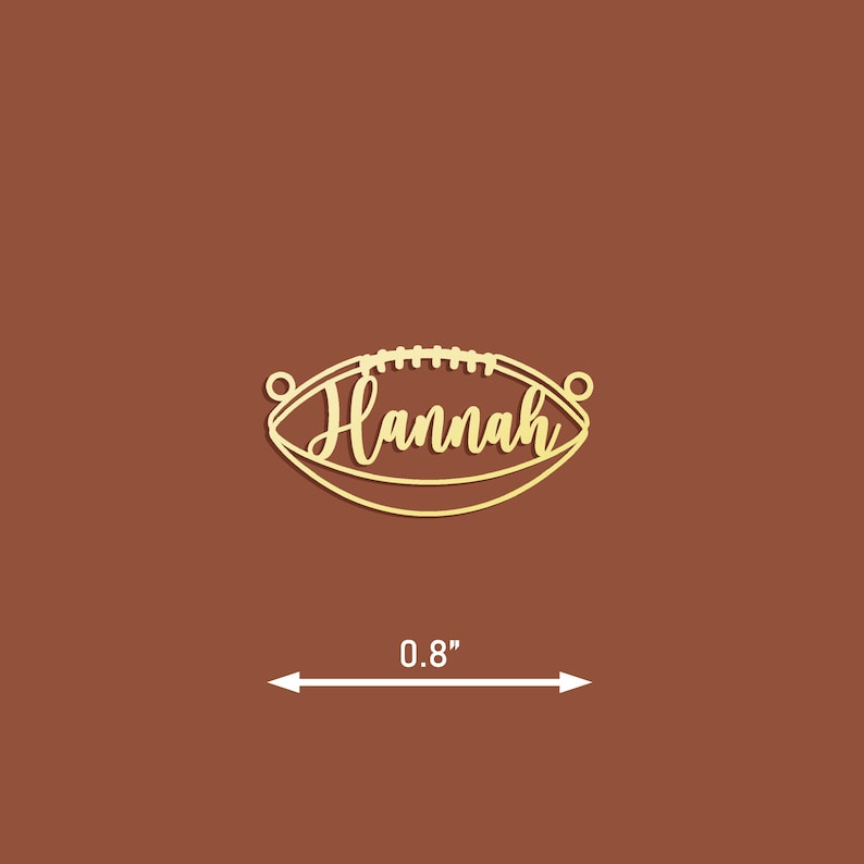 May include: Gold-coloured metal football charm with the name "Hannah" inscribed on it. The charm is 0.8 inches in diameter.