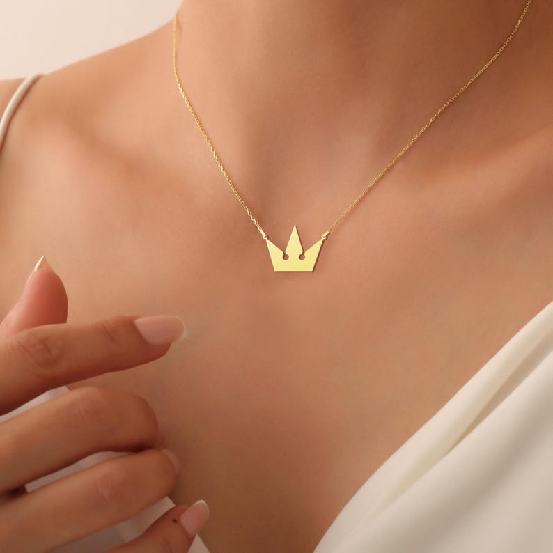 Peut inclure: Un collier en cha&icirc;ne dor&eacute;e avec un pendentif en forme de couronne simple.