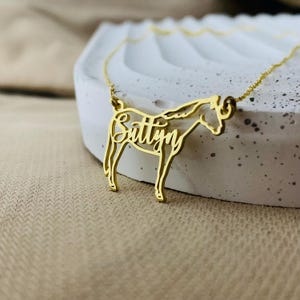 Peut inclure: Collier en or en forme de cheval avec le nom "Suttyn" d&eacute;coup&eacute; dans le corps du cheval.