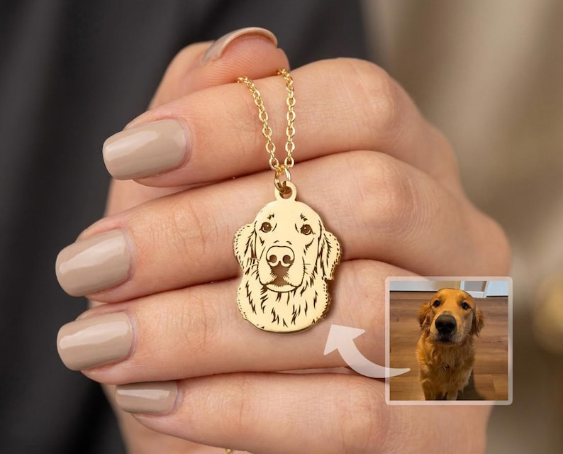 May include: A gold-colored pendant necklace featuring a detailed engraving of a Golden Retriever's face. The pendant hangs from a delicate chain. A small photo of a Golden Retriever is in the lower right corner.