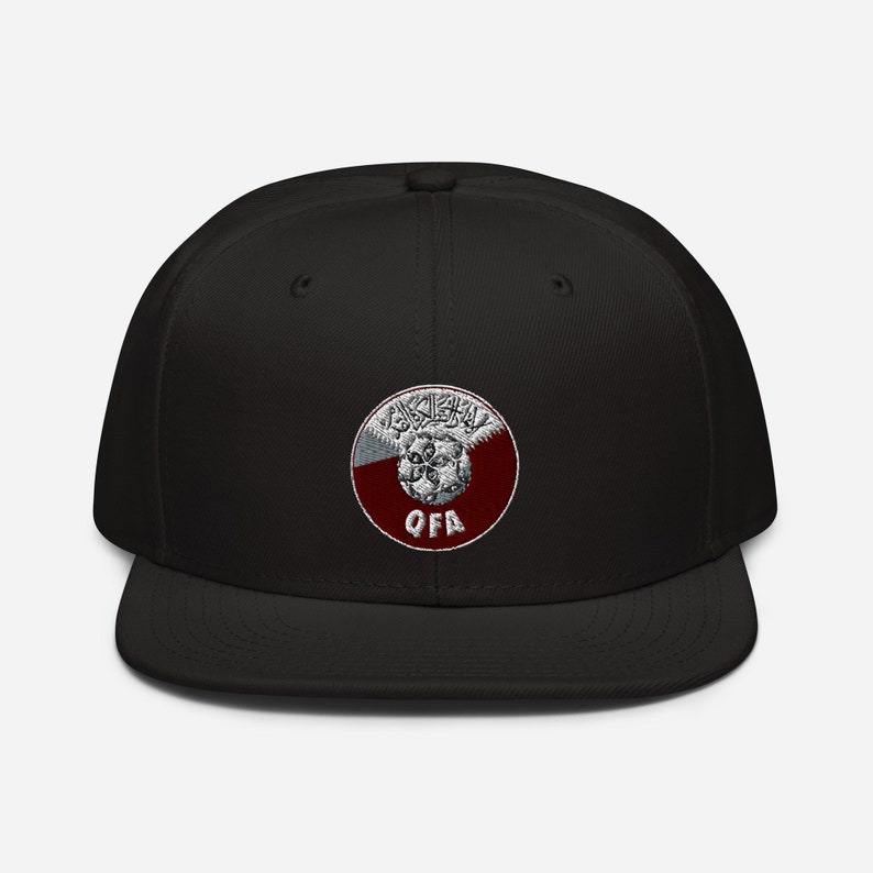 May include: Black baseball cap with a flat brim. The cap features a circular emblem with Arabic script, a maroon and white design, and the letters "QFA". The cap is a classic, casual accessory.
