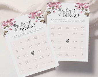 May include: Two pink and white baby shower bingo cards with floral accents. The cards have a list of baby-related items to mark off as gifts are opened. The text on the card reads "Baby Bingo".