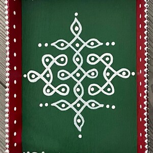 May include: A green wooden tray with a white geometric design painted on the surface. The tray has a red border with white dots and a silver beaded trim.