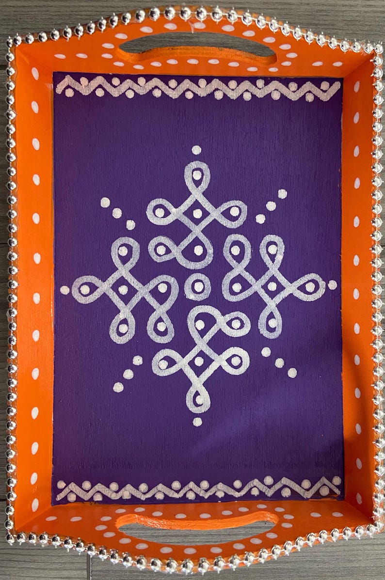May include: A wooden serving tray with an orange border and white polka dots. The tray has a purple interior with a white geometric design.