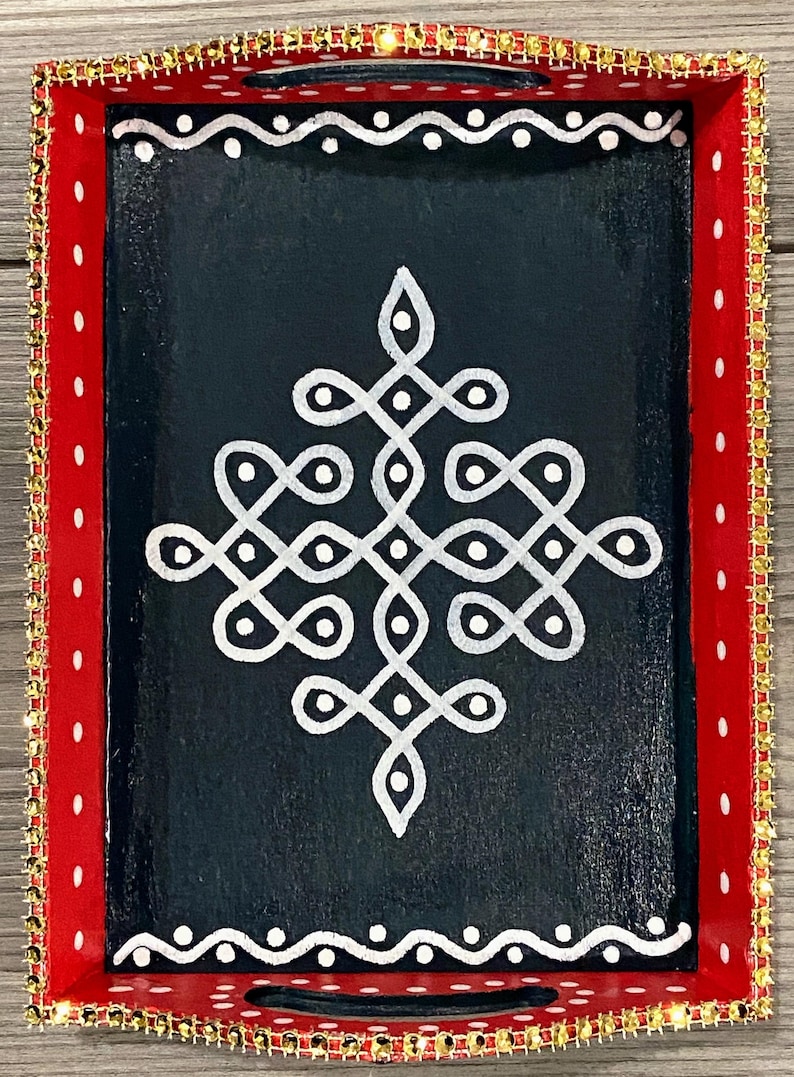 May include: A red wooden tray with a gold trim and a white geometric design on a black background.