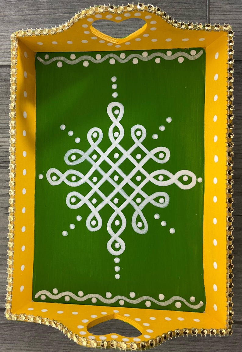 May include: A yellow wooden tray with a green center and white painted design. The tray has a heart-shaped cutout handle and a gold beaded trim.