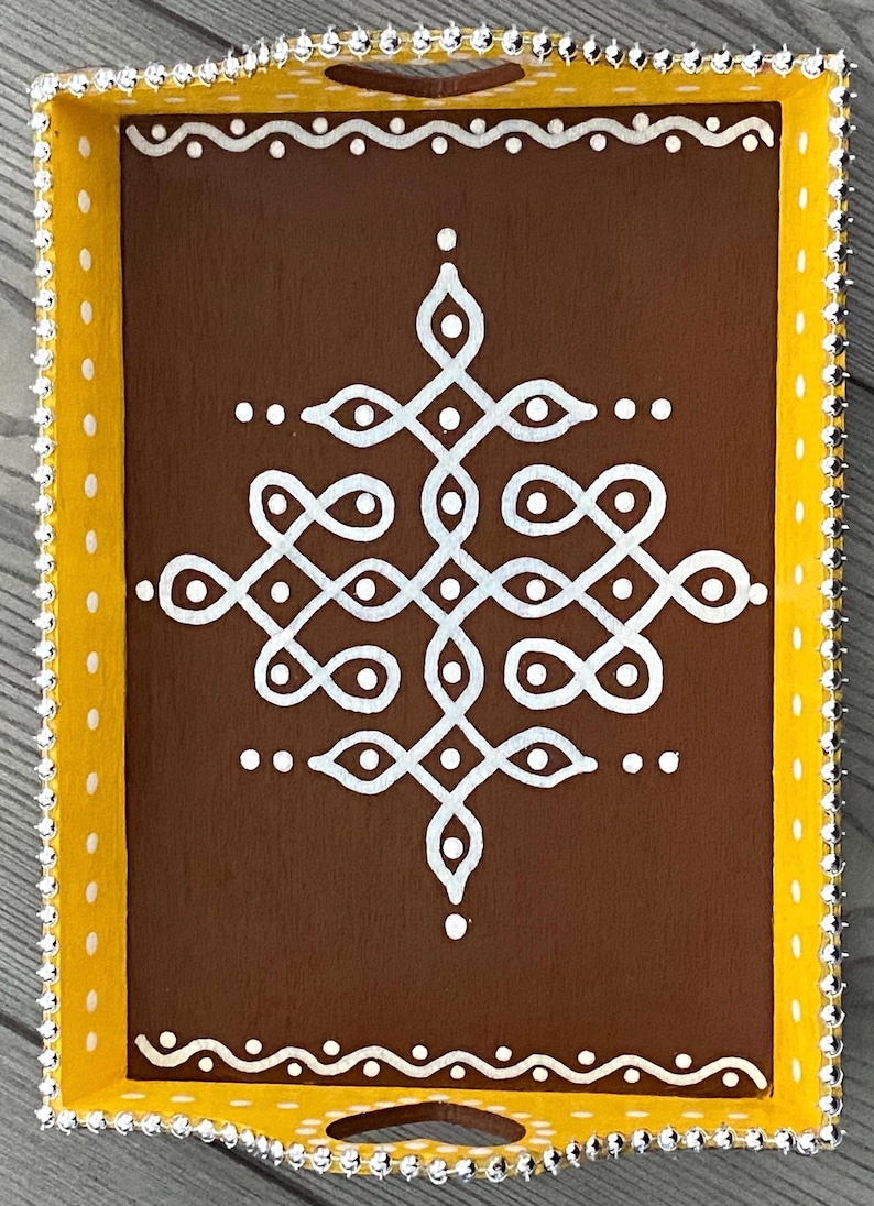 May include: A brown wooden tray with a yellow border and white decorative design. The tray has a beaded trim around the edge.