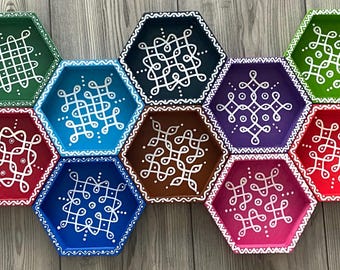 May include: Eight hexagonal trays with white geometric designs painted on a variety of colored backgrounds. The trays are arranged in a circular pattern.