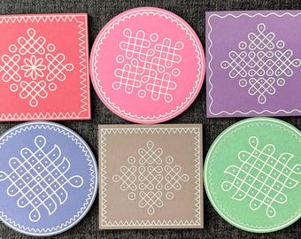 May include: A collection of colorful coasters with intricate white geometric designs. The coasters are in various shapes, including squares and circles, and feature a range of pastel colors such as pink, purple, and green. The designs are symmetrical and detailed.