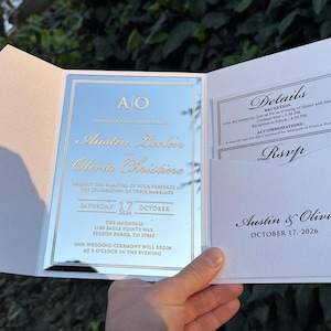 May include: A wedding invitation suite with a mirrored finish. The invitation features the names "Austin & Olivia" and event details. The suite includes RSVP and details cards. The date is October 17, 2026.