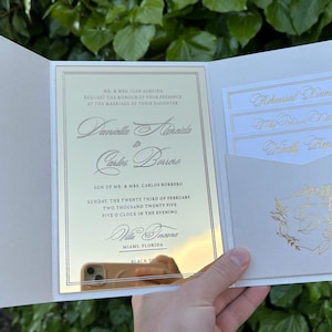 K&ouml;nnte beinhalten: Elfenbein-Hochzeitseinladung mit goldfarbenem Text. Die Einladung enth&auml;lt die Namen des Paares, Datum, Uhrzeit und Ort. Zus&auml;tzliche Karten f&uuml;r das Probeessen, den Empfang und die Antwort sind enthalten.