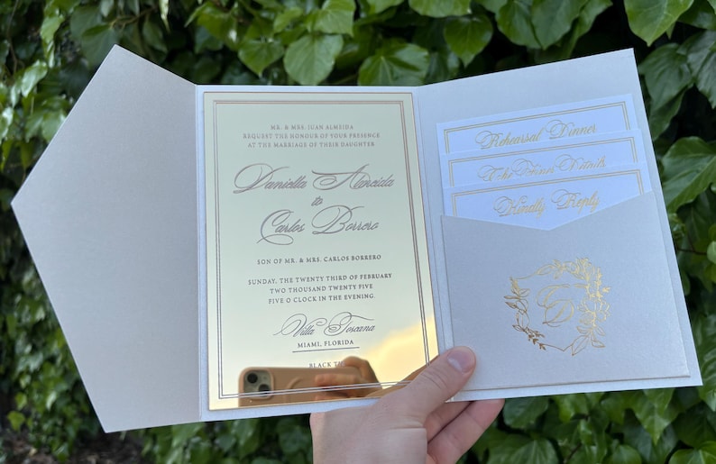 K&ouml;nnte beinhalten: Elfenbein-Hochzeitseinladung mit goldfarbenem Text. Die Einladung enth&auml;lt die Namen des Paares, Datum, Uhrzeit und Ort. Zus&auml;tzliche Karten f&uuml;r das Probeessen, den Empfang und die Antwort sind enthalten.