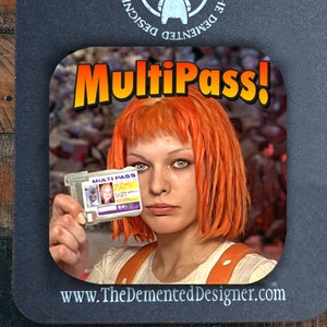 May include: A black and white coaster with a red and yellow graphic that says "MultiPass!" and features a woman with orange hair holding a card that says "MultiPass". The coaster has a white circle with a cartoon devil in the center and the text "The Demented Designer" around the circle. The text "www.TheDementedDesigner.com" is at the bottom of the coaster.