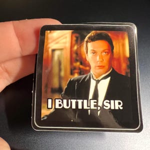May include: A black and white sticker with a photo of a man in a tuxedo and the text "I BUTTLE, SIR".