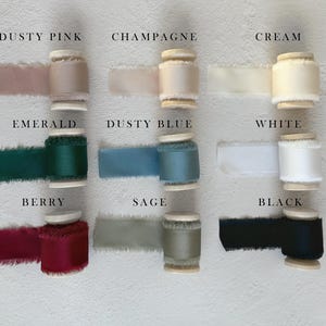 May include: Nine spools of frayed-edge ribbon arranged in a grid, labeled with colors: Dusty Pink, Champagne, Cream, Emerald, Dusty Blue, White, Berry, Sage, and Black. Each spool features a smooth, solid-colored fabric ribbon with raw, textured edges.